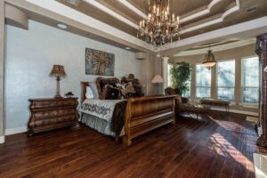 Phòng ngủ chính sang trọng với sàn gỗ cứng hickory, đèn chùm và đồ nội thất trang nhã